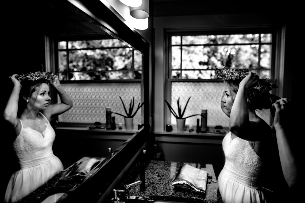 Bride getting ready with maid of honor, wedding dress and flower crown by vermont wedding photographer andy madea