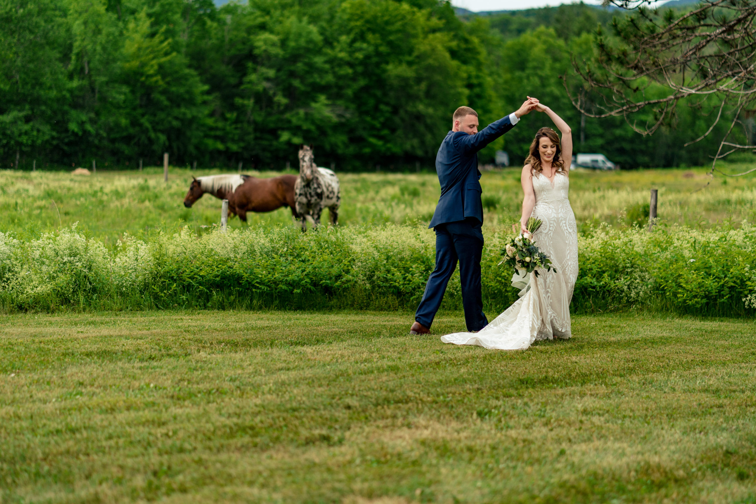 bride and groom dancing in a field with horses