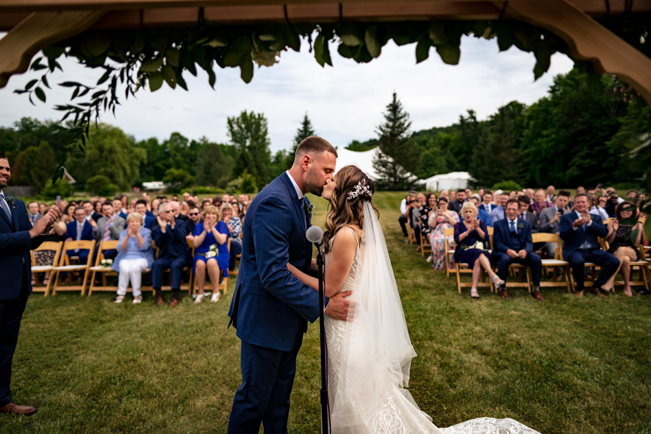 bride and groom's first kiss, looking at outdoor wedding ceremony crowd at Topnotch Resort, Stowe Vermont